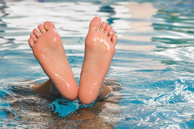 Ľudské chodidlá trčiace z vody v bazéne.jpg